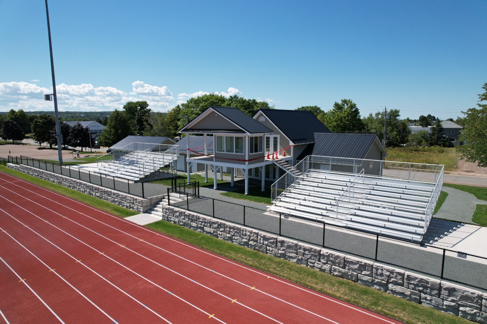 Aluminum grandstands and press pavilion set on a stone retaining wall beside the track